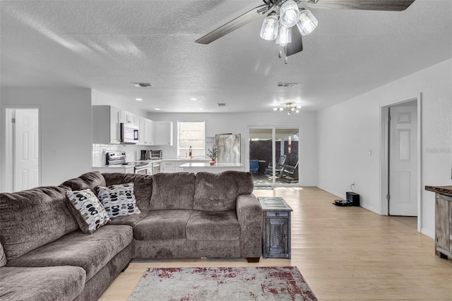 15950 Adobe Dr, Hudson, FL 34667 - living area featuring light wood-style floors, ceiling fan, and a textured ceiling