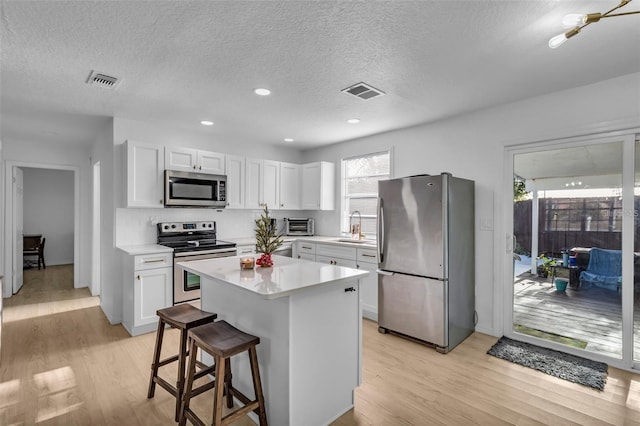 15950 Adobe Dr, Hudson, FL 34667 - kitchen featuring appliances with stainless steel finishes, a textured ceiling, light wood-style floors, light countertops, and white cabinets