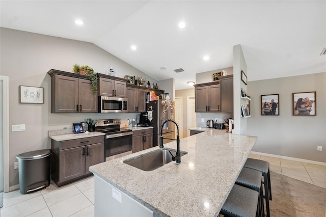 11034 Flock Ave, Weeki Wachee, FL 34613 - kitchen with appliances with stainless steel finishes, dark brown cabinets, a peninsula, light tile patterned flooring, and a breakfast bar area