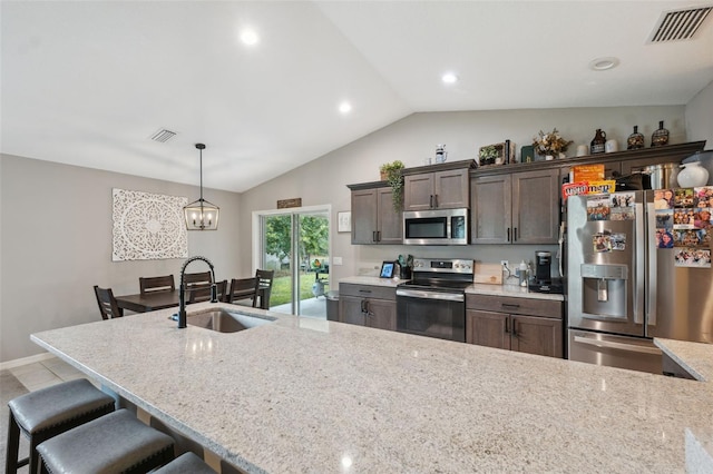 11034 Flock Ave, Weeki Wachee, FL 34613 - kitchen featuring appliances with stainless steel finishes, a kitchen breakfast bar, dark brown cabinets, vaulted ceiling, and light stone countertops