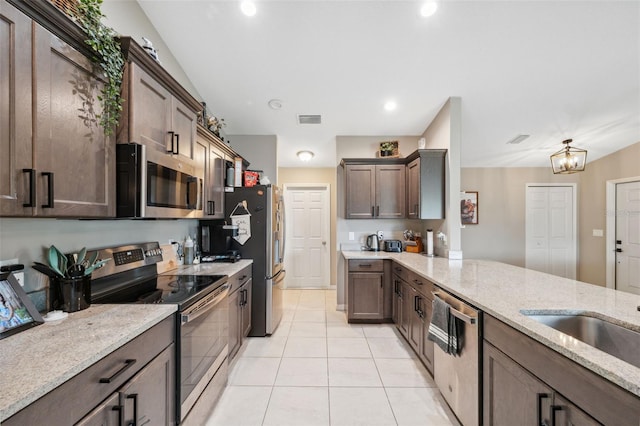 11034 Flock Ave, Weeki Wachee, FL 34613 - kitchen with appliances with stainless steel finishes, light stone counters, dark brown cabinetry, light tile patterned floors, and recessed lighting