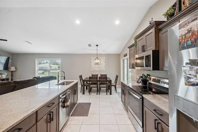 11034 Flock Ave, Weeki Wachee, FL 34613 - kitchen with stainless steel appliances, lofted ceiling, light tile patterned floors, hanging light fixtures, and open floor plan