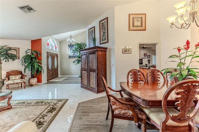 dining room featuring a chandelier, light marble finish flooring, and lofted ceiling