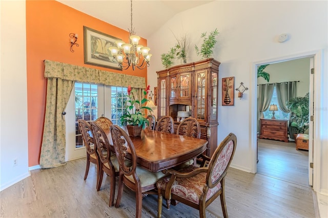 dining room with a chandelier, french doors, light wood-style flooring, and high vaulted ceiling