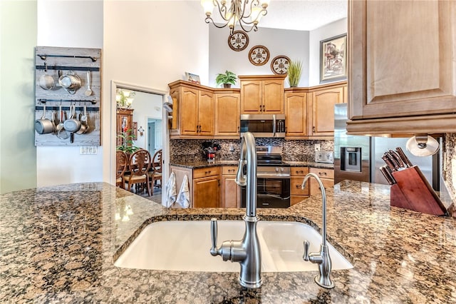 kitchen featuring stainless steel appliances, tasteful backsplash, dark stone countertops, and a high ceiling