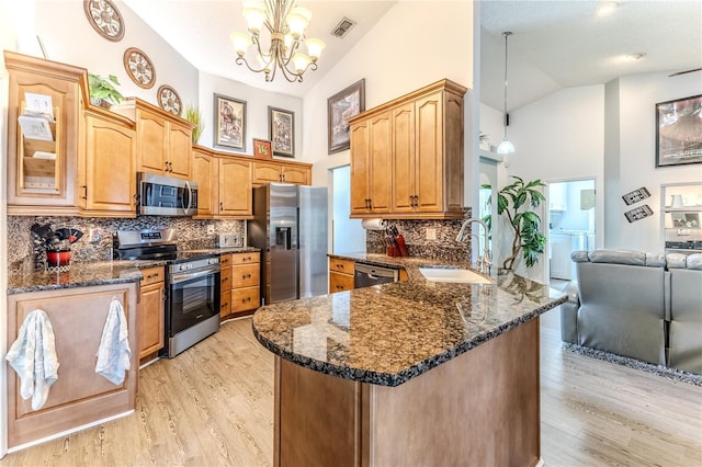 kitchen with stainless steel appliances, a peninsula, high vaulted ceiling, a chandelier, and decorative backsplash