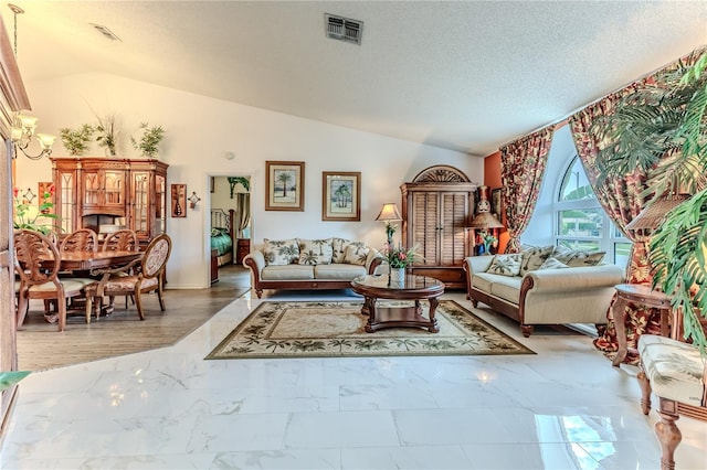 living area with lofted ceiling, marble look tile flooring, and a textured ceiling
