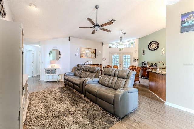 living room with ceiling fan, light wood finished floors, and french doors