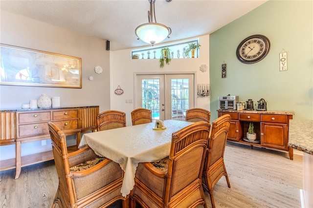 dining room featuring light wood finished floors, french doors, and a textured ceiling