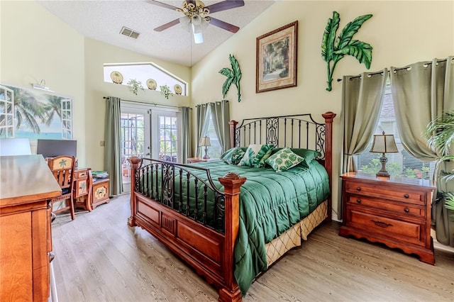 bedroom with lofted ceiling, light wood-style floors, access to outside, french doors, and a textured ceiling