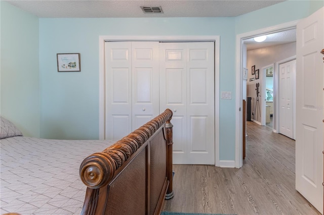 bedroom with light wood finished floors and a closet