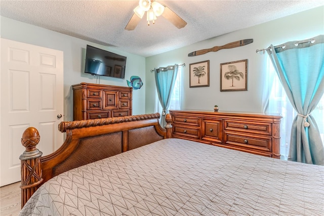 bedroom with a textured ceiling, a ceiling fan, and wood finished floors