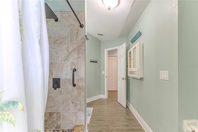 full bathroom featuring tiled shower and wood finished floors