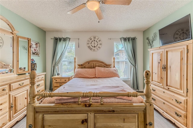 bedroom featuring a textured ceiling, multiple windows, light wood finished floors, and a ceiling fan