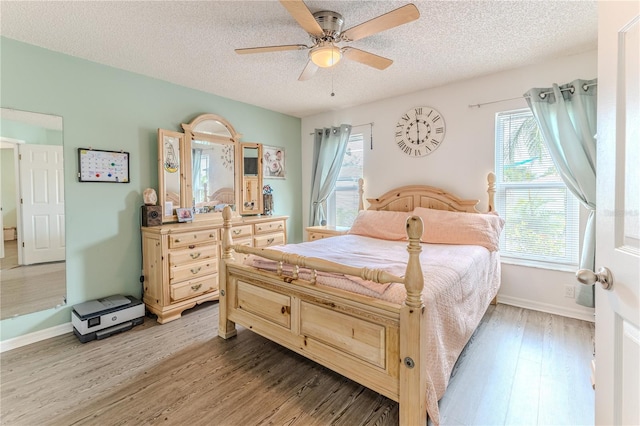 bedroom with light wood-type flooring, a textured ceiling, and a ceiling fan
