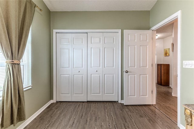 unfurnished bedroom with wood finished floors, a closet, and a textured ceiling