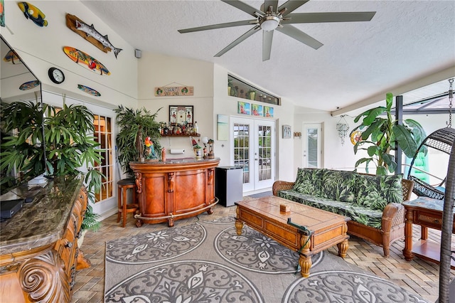 living room with lofted ceiling, a textured ceiling, french doors, and ceiling fan