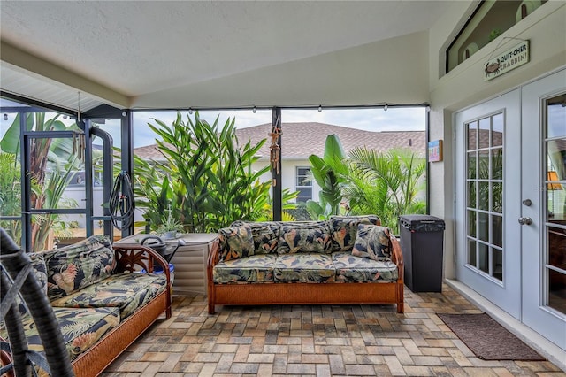 sunroom featuring french doors, brick floors, vaulted ceiling, and healthy amount of natural light