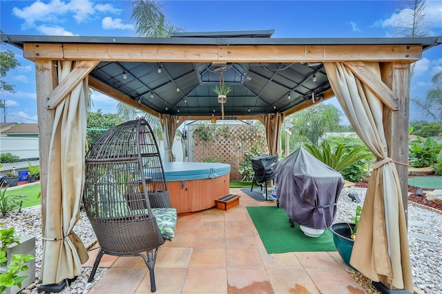 view of patio / terrace featuring a hot tub, a gazebo, and grilling area