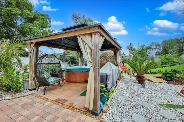 fenced backyard with a hot tub, a gazebo, and a patio