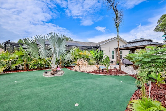 view of yard with a gazebo, glass enclosure, and an area to practice putting