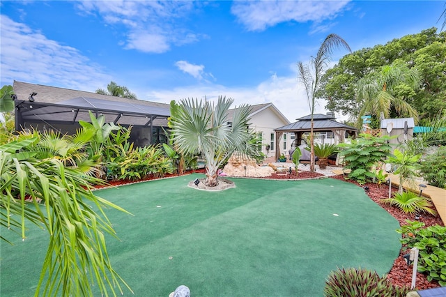 view of yard with a gazebo, a putting green, and glass enclosure