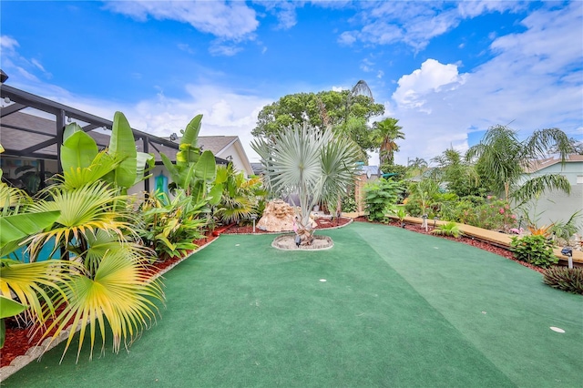 view of yard featuring a putting green and glass enclosure