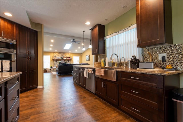 7550 Jomel Dr, Weeki Wachee, FL 34607 - kitchen featuring stainless steel appliances, a ceiling fan, decorative backsplash, dark brown cabinetry, and a textured ceiling