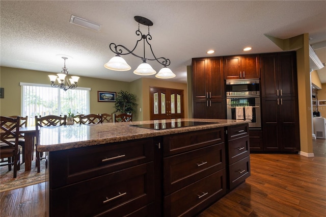 7550 Jomel Dr, Weeki Wachee, FL 34607 - kitchen with stainless steel appliances, a chandelier, dark wood-style floors, hanging light fixtures, and a textured ceiling