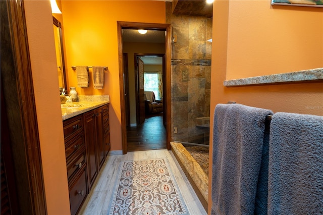 7550 Jomel Dr, Weeki Wachee, FL 34607 - bathroom featuring vanity, wood finished floors, and a tile shower