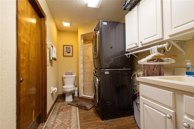 7550 Jomel Dr, Weeki Wachee, FL 34607 - full bath with stacked washer / drying machine, a textured ceiling, wood finished floors, vanity, and a shower with shower door