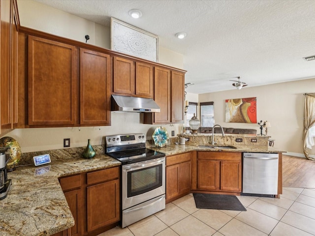 4481 Birchfield Loop, Spring Hill, FL 34609 - kitchen featuring stainless steel appliances, under cabinet range hood, a peninsula, brown cabinets, and a textured ceiling