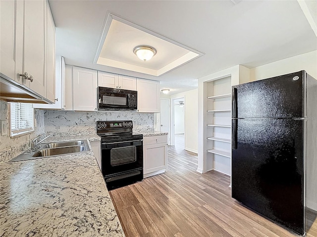 6341 Hyperion Dr, Port Richey, FL 34668 - kitchen with black appliances, a raised ceiling, light wood-style flooring, white cabinetry, and tasteful backsplash