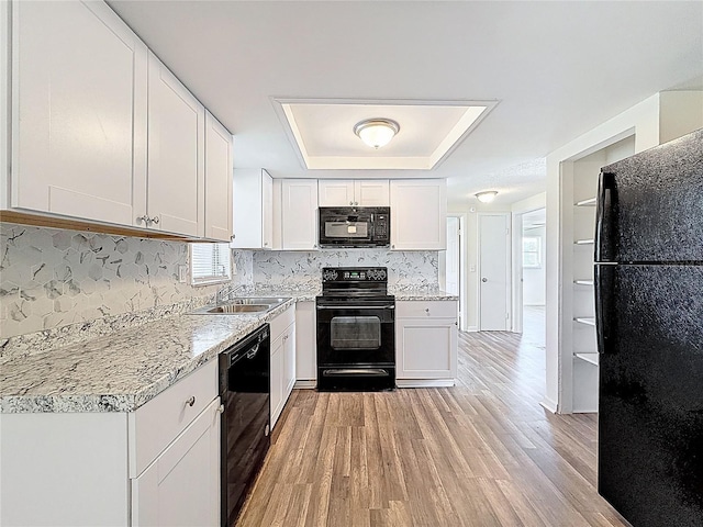 6341 Hyperion Dr, Port Richey, FL 34668 - kitchen with black appliances, a tray ceiling, plenty of natural light, and light wood-style floors