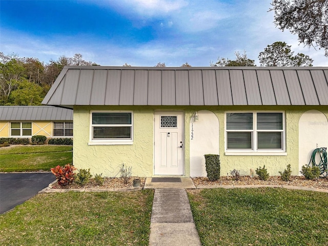 11722 Carissa Ln Unit 49A, New Port Richey, FL 34654 - view of front of house featuring stucco siding, a front lawn, and a metal roof