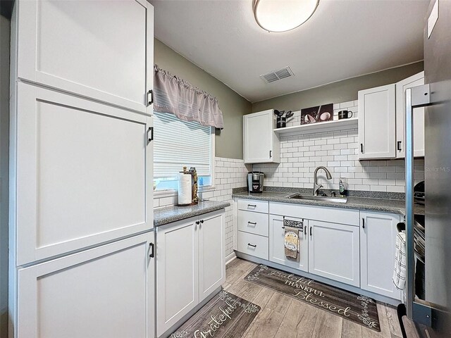 11722 Carissa Ln Unit 49A, New Port Richey, FL 34654 - kitchen featuring open shelves, white cabinetry, light wood-style floors, dark countertops, and tasteful backsplash