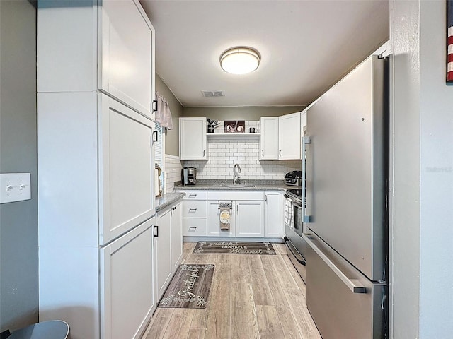 11722 Carissa Ln Unit 49A, New Port Richey, FL 34654 - kitchen featuring freestanding refrigerator, range, light wood-type flooring, open shelves, and white cabinetry