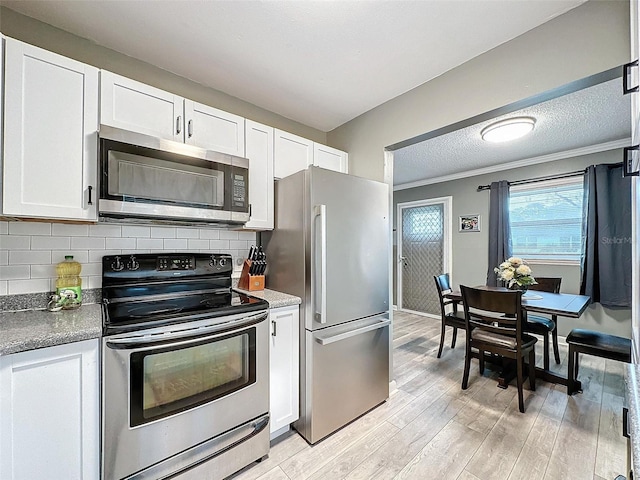 11722 Carissa Ln Unit 49A, New Port Richey, FL 34654 - kitchen with appliances with stainless steel finishes, white cabinetry, light wood-style flooring, decorative backsplash, and a textured ceiling