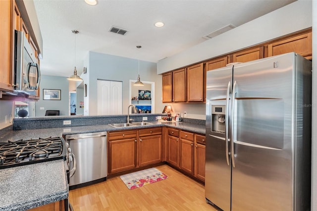 3450 Ferrell St, New Port Richey, FL 34655 - kitchen featuring appliances with stainless steel finishes, brown cabinetry, light wood finished floors, hanging light fixtures, and recessed lighting