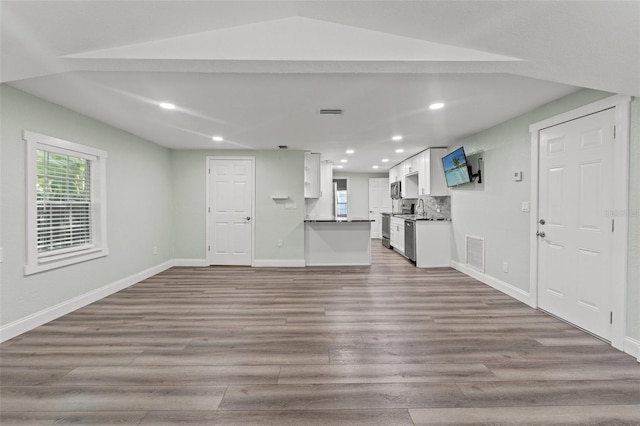5724 Casson Ave, New Port Richey, FL 34652 - unfurnished living room featuring wood finished floors, recessed lighting, and lofted ceiling