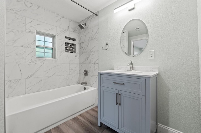 5724 Casson Ave, New Port Richey, FL 34652 - full bath with wood finished floors, a textured wall, vanity, and shower / tub combination