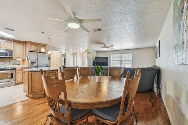 1071 Lexington Ct, Largo, FL 33771 - dining room with ceiling fan, light wood-type flooring, and a textured ceiling