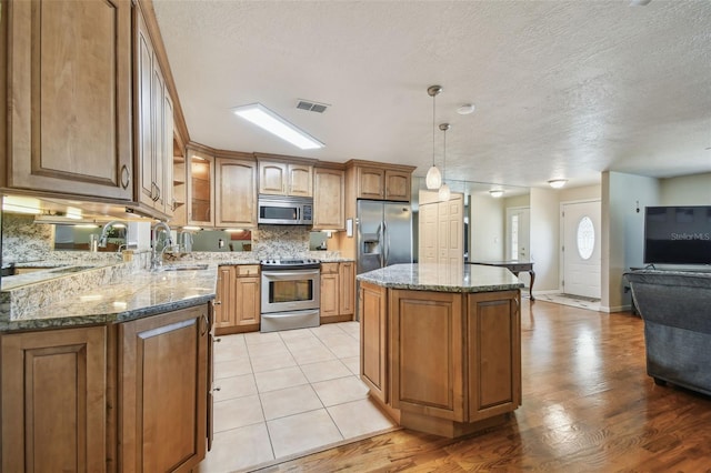 1071 Lexington Ct, Largo, FL 33771 - kitchen with stainless steel appliances, a kitchen island, tasteful backsplash, stone counters, and brown cabinetry