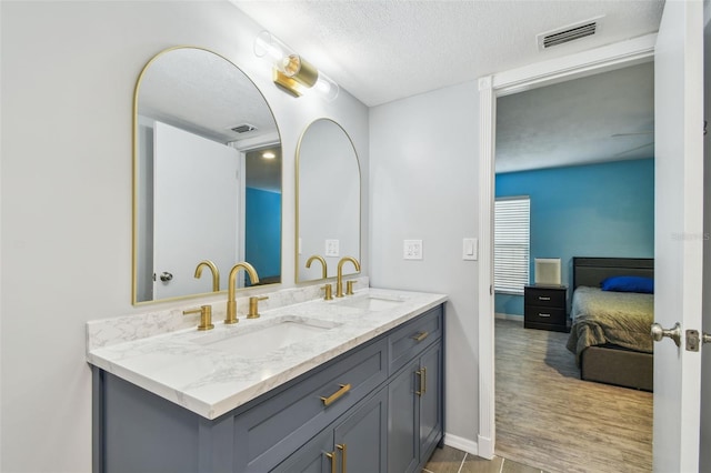 1071 Lexington Ct, Largo, FL 33771 - bathroom with double vanity, ensuite bath, a textured ceiling, and wood finished floors
