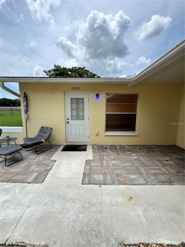 12104 Boynton Ln, New Port Richey, FL 34654 - view of exterior entry featuring stucco siding and a patio area