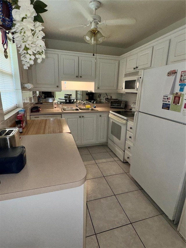 12104 Boynton Ln, New Port Richey, FL 34654 - kitchen with white appliances, white cabinets, ceiling fan, light tile patterned flooring, and light countertops