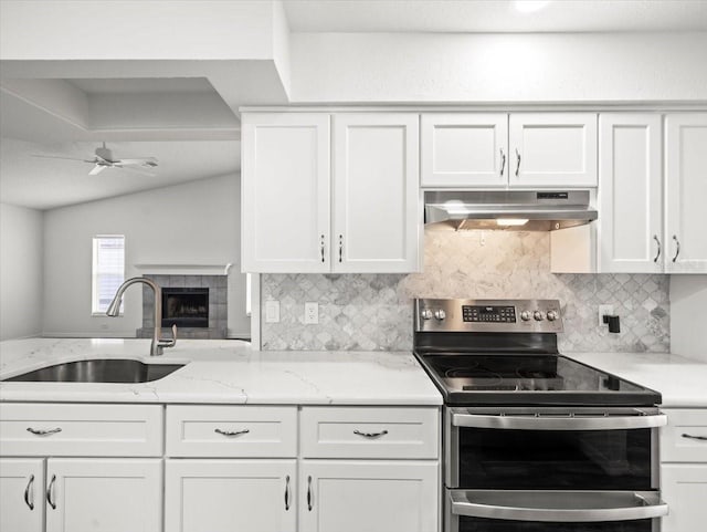 15430 Oakcrest Cir, Brooksville, FL 34604 - kitchen with double oven range, under cabinet range hood, backsplash, white cabinetry, and lofted ceiling