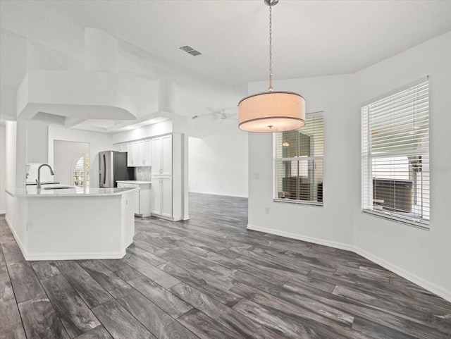 15430 Oakcrest Cir, Brooksville, FL 34604 - kitchen featuring freestanding refrigerator, white cabinetry, dark wood finished floors, light countertops, and pendant lighting