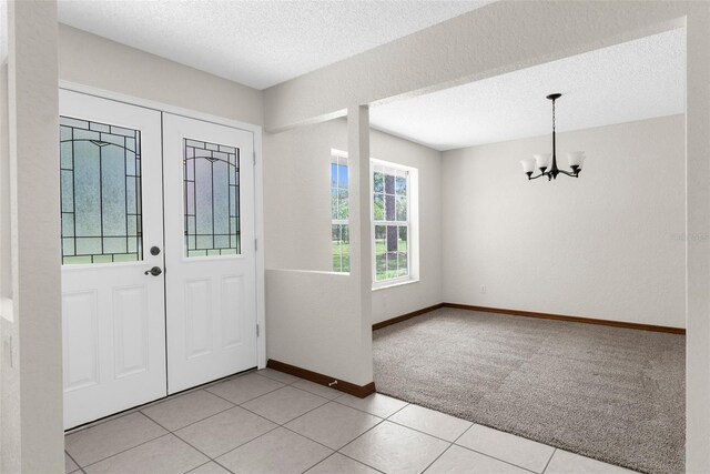 14645 Spellman Ct, Spring Hill, FL 34610 - entrance foyer featuring a chandelier, light colored carpet, a textured ceiling, and light tile patterned floors