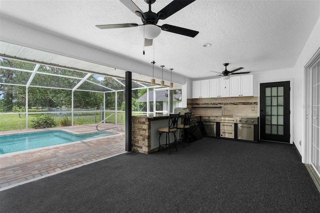 14645 Spellman Ct, Spring Hill, FL 34610 - swimming pool featuring glass enclosure, a patio area, a ceiling fan, and an outdoor kitchen